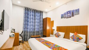 Una habitación de hotel con una cama grande, cabecero de madera, un escritorio y una silla.