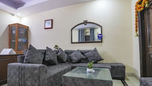 Una sala de estar con un sofá seccional gris, una mesa de centro de vidrio, un mueble de madera y un espejo en la pared.