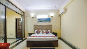 Habitación de hotel con una cama grande, una mesita de noche, un aire acondicionado de pared y un cuadro enmarcado.