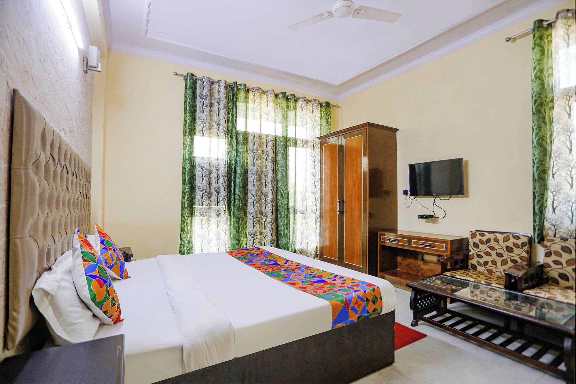 Habitación de hotel con cama, televisión, armario y zona de estar.