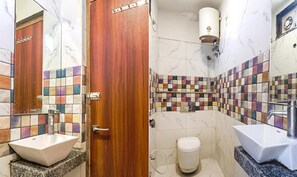 A bathroom with a wooden door, a tiled shower wall, and two sinks.