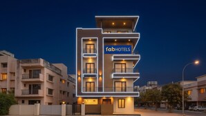 Um hotel moderno de vários andares com um destaque para a placa 'fabHOTELS', com varandas e fachada bem iluminada.