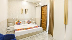 Quarto com cama, mesas de cabeceira, ar condicionado, ventoinha no teto e porta de madeira.