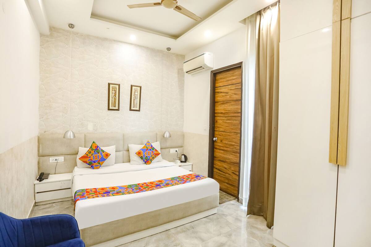 Un dormitorio con cama, mesitas de noche, aire acondicionado, ventilador de techo y una puerta de madera.