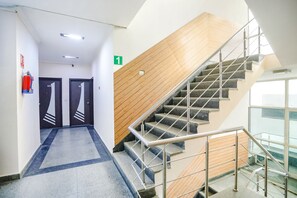 A modern hotel corridor with a staircase leading to a second floor. - FabHotel F9 H Block Sector 51 (Noida)