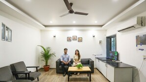 Un espace de bureau moderne où deux personnes sont assises sur un canapé, devant une table basse et un bureau équipé d’un écran d’ordinateur.