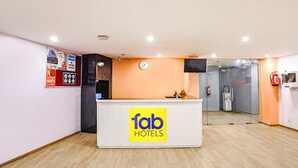 A reception desk with a 'fab hotels' sign, a clock, and a fire extinguisher on the wall. - FabHotel Noida Grand (Noida)