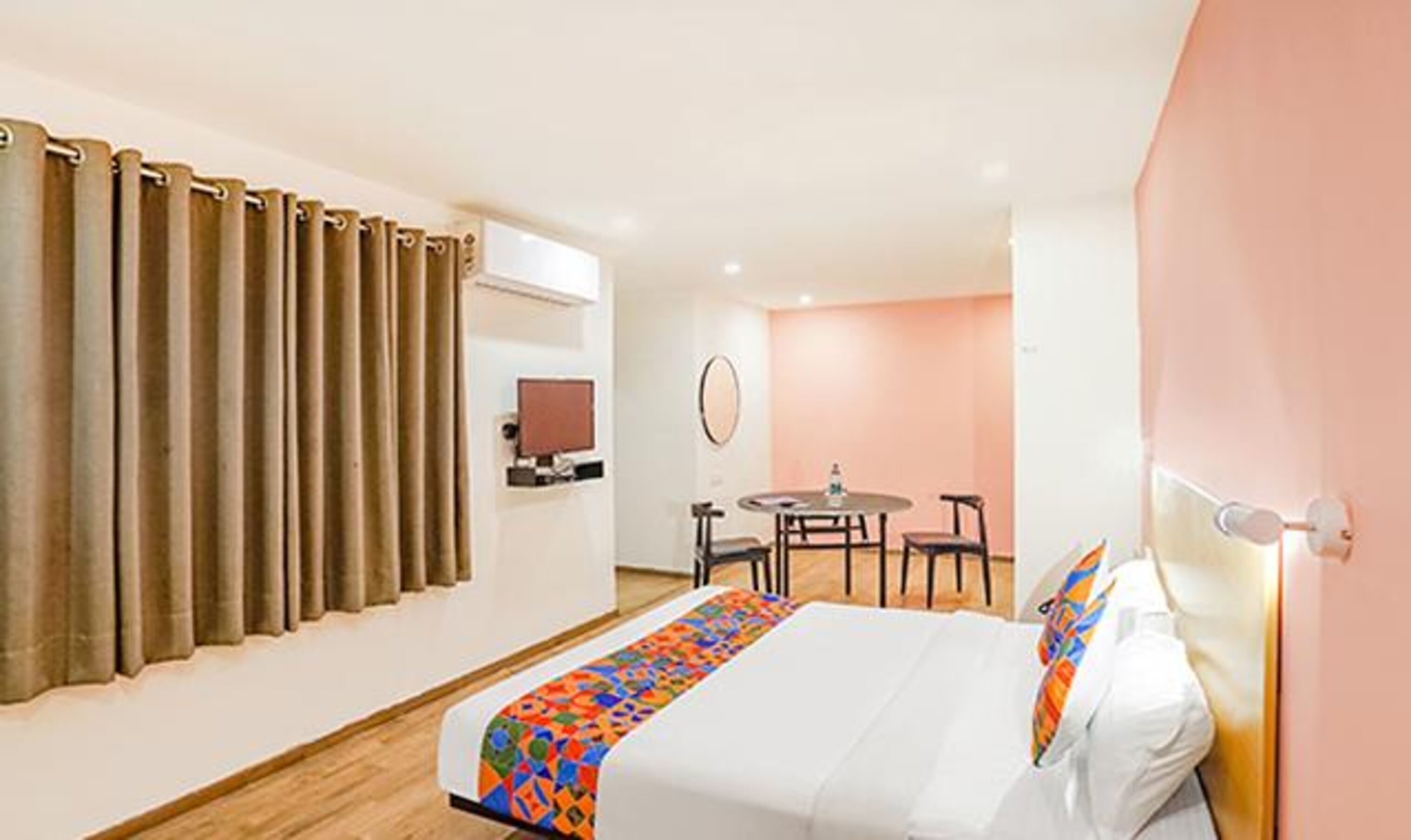 A hotel room with a bed, a desk, a chair, a television, and a window with curtains.