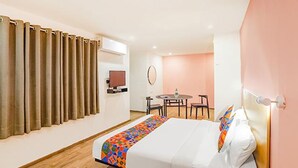 A hotel room with a bed, a desk, a chair, a television, and a window with curtains. - FabHotel Noida Grand (Noida)