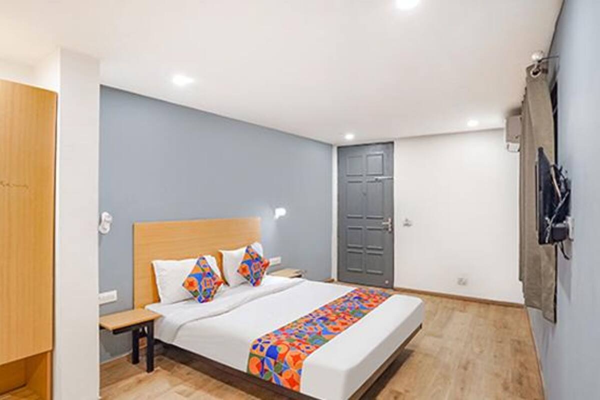 A bedroom with a bed, wooden wardrobe, and a grey door.