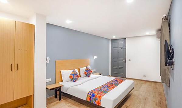A bedroom with a bed, wooden wardrobe, and a grey door. - FabHotel Noida Grand (Noida)