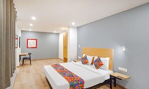 A modern hotel room with a large bed, a bedside table, and a small desk. - FabHotel Noida Grand (Noida)