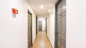 A narrow hallway with wooden flooring and grey doors on both sides. - FabHotel Noida Grand (Noida)