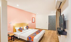 A bedroom with a bed, a desk, a chair, a television, and a door. - FabHotel Noida Grand (Noida)