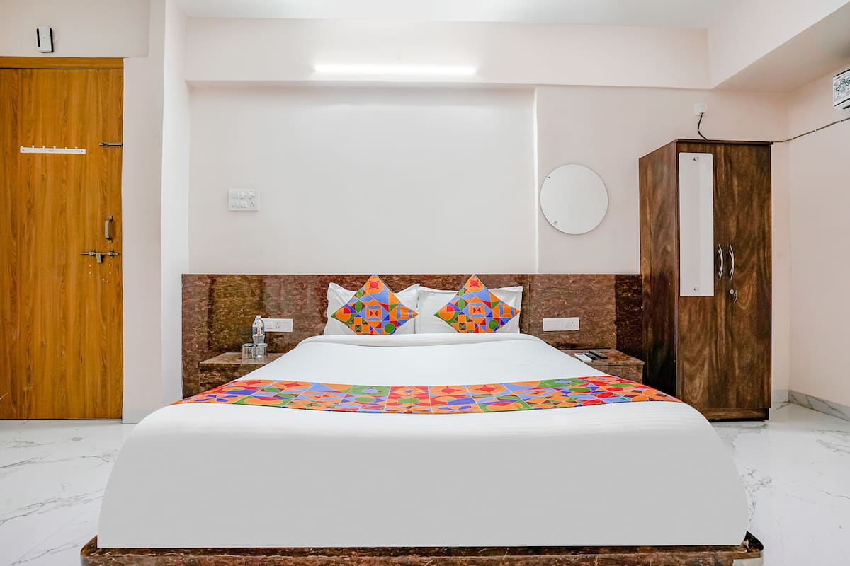 A bedroom with a bed, a wardrobe, a bedside table, and a wall-mounted round mirror.