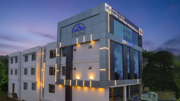 A modern hotel building with a prominent logo, a sign for the Ramee Abirami Residency, and a visible entrance with steps. - Fabhotel Abirami Grand Inn (Kodaikanal)