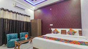A hotel room with a bed, a sofa, a wooden table, and a wardrobe. - Fabexpress Ss Grand (Lucknow)