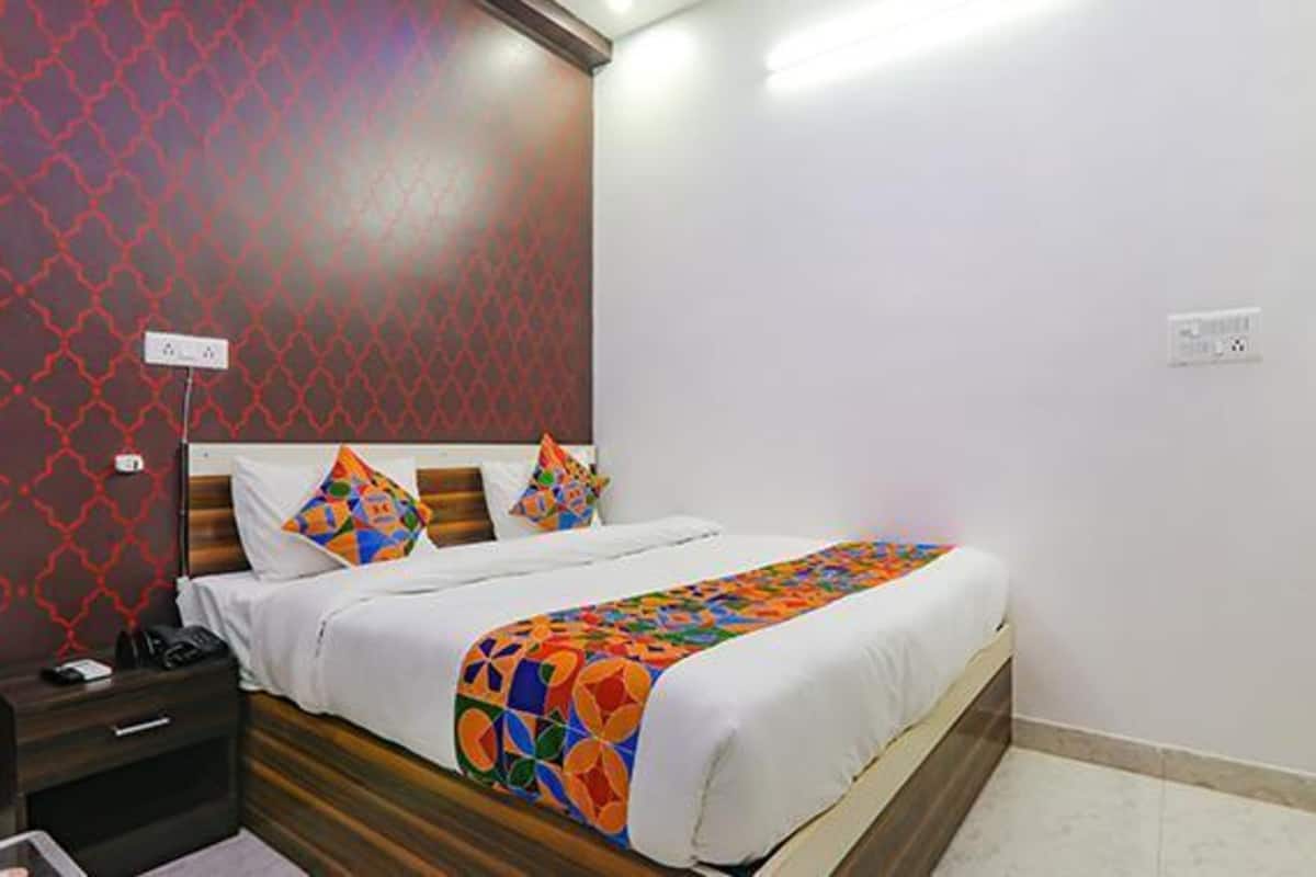 Una habitación de hotel con una cama, una mesita de noche y una pared con diseño geométrico.
