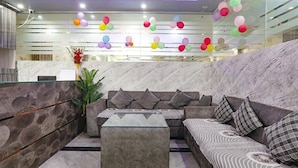 A modern lobby with a marble reception desk, a sectional sofa, and colorful balloons on the ceiling. - Fabexpress Ss Grand (Lucknow)