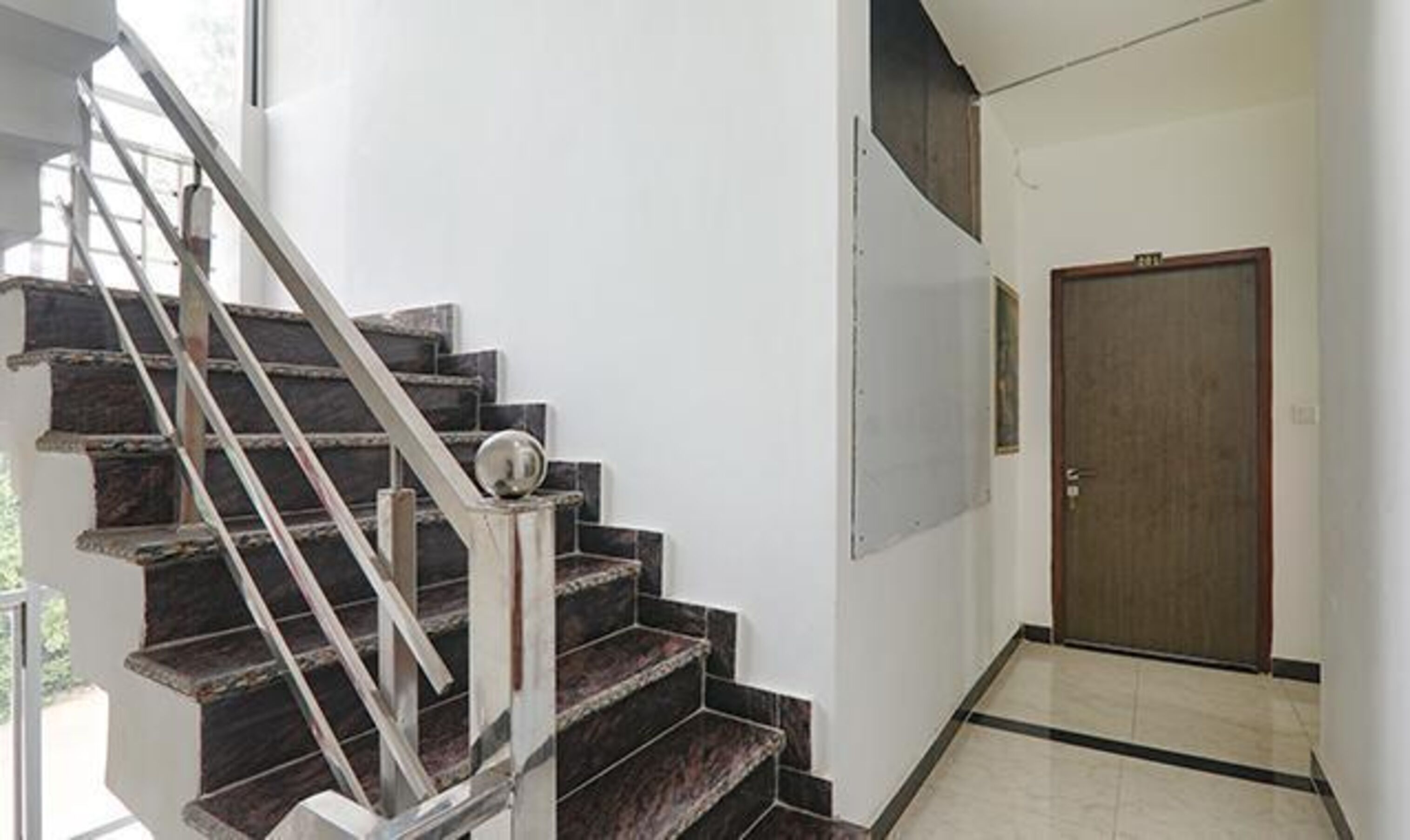 A staircase with dark marble steps and metal railings leading to a door.