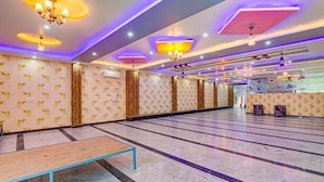 A spacious indoor area with patterned walls, a long row of seating, and a central table. - Fabexpress Ss Grand (Lucknow)