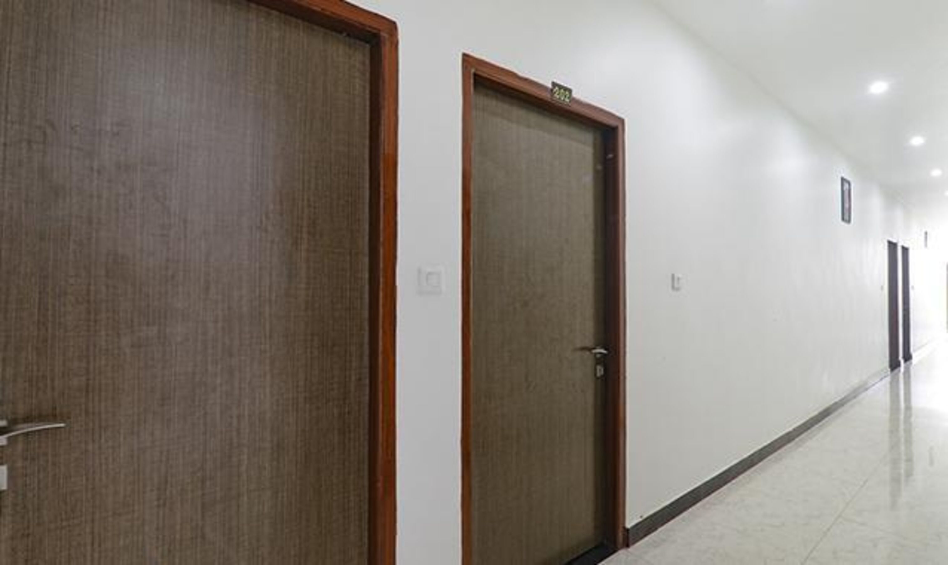 Un couloir avec des portes en bois et un sol carrelé.
