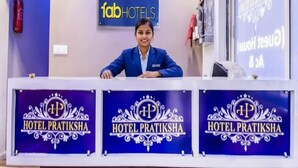 A hotel reception desk with a receptionist, a sign for 'fabHOTELS', and multiple 'HOTEL PRATIKSHA' signs. - FabHotel Pratiksha (Ahmedabad)