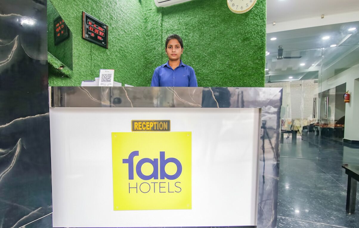 Bancada de recepção na Fab Hotels, com parede verde e relógio.