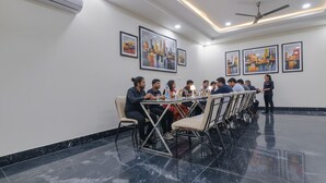 A conference room with a long table, chairs, and a standing person. - FabHotel Golden Gate I Amritsar (Amritsar)
