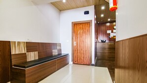 A reception area with a wooden reception desk, a wooden door, and a tiled floor.