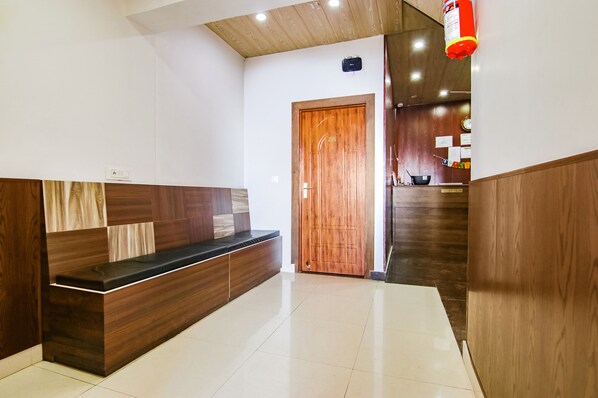 Un espace d’accueil comprenant un comptoir de réception en bois, une porte en bois et un sol carrelé.