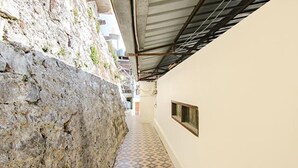 A narrow corridor with a stone wall on one side and a tiled floor.