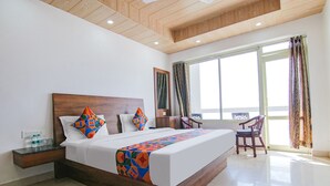 A hotel room with a large bed, a wooden headboard, a nightstand, a chair, and a large window with curtains.