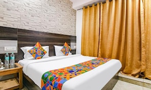 A hotel room with a bed, a nightstand, a water bottle, and a patterned throw blanket.