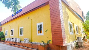 A yellow building with a red roof, air conditioning units, and a sign reading "Fabi Hotels". - Via Airport Stay Inn - Nr, Rajiv Gandhi International Airport (Hyderabad)