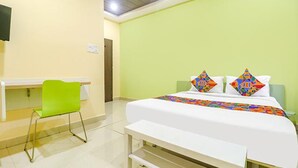 A hotel room with a bed, a desk, and a green chair. - Via Airport Stay Inn - Nr, Rajiv Gandhi International Airport (Hyderabad)