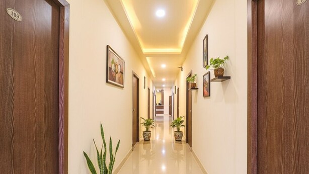 A hallway with wooden doors, potted plants, and framed artwork on the walls. - Via Airport Stay Inn - Nr, Rajiv Gandhi International Airport (Hyderabad)