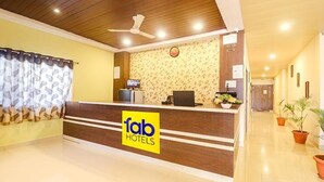 A hotel reception area with a wooden reception desk, a ceiling fan, and a reception counter with a 'fab hotels' sign. - Via Airport Stay Inn - Nr, Rajiv Gandhi International Airport (Hyderabad)