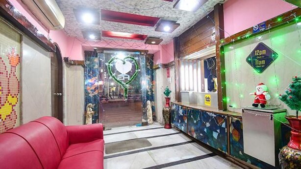 A reception area with a red couch, a heart-shaped decoration, and a Christmas tree with a Santa figure. - FabExpress Gardenia (Kolkata)
