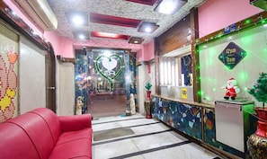 A reception area with a red couch, a heart-shaped decoration, and a Christmas tree with a Santa figure. - FabExpress Gardenia (Kolkata)