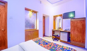 Una habitación de hotel con cama, escritorio, silla, televisión y armario.