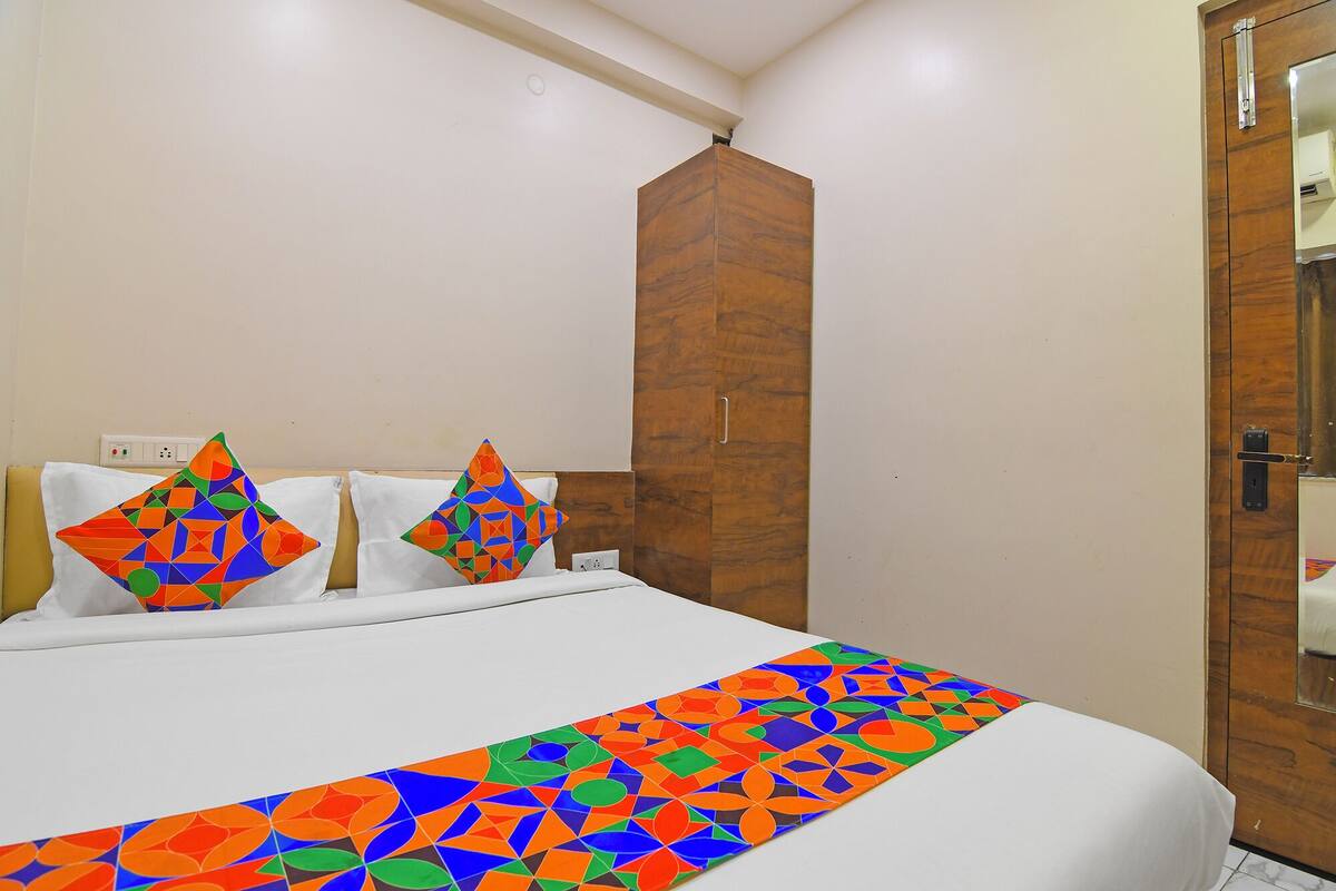 Ein Hotelzimmer mit einem Bett, zwei Kissen, einem Holzschrank und einer Tür.