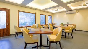 A conference room with a long table, multiple chairs, large windows, and a ceiling fan. - Fabhotel Phoenix Brookfield (Bengaluru)