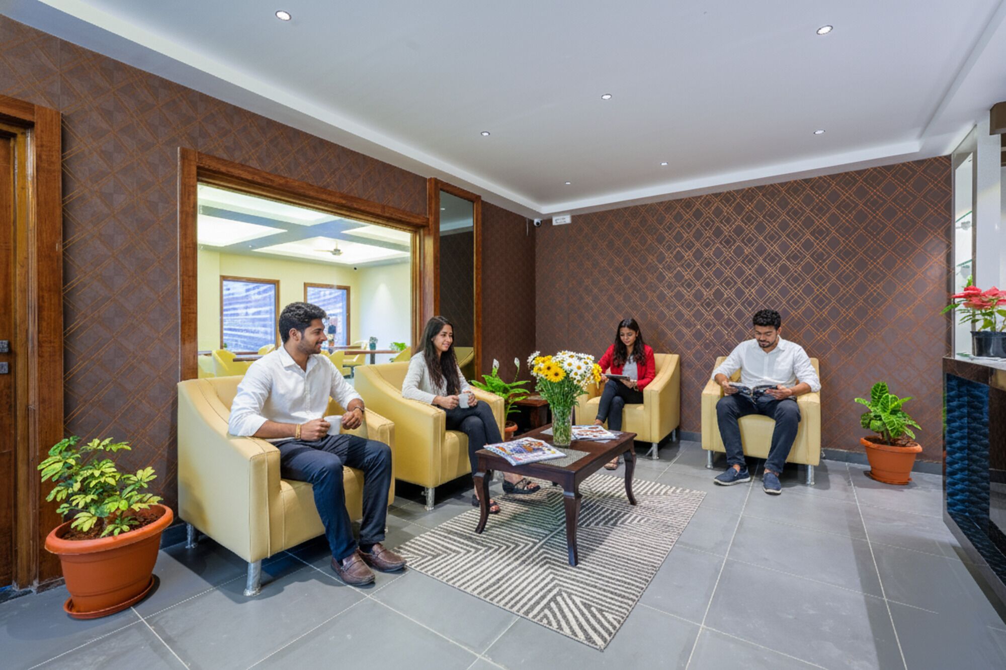 A modern waiting area with leather sofas, a coffee table, and potted plants.