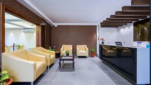 A modern reception area with a reception desk, two armchairs, a coffee table, and a patterned wall. - Fabhotel Phoenix Brookfield (Bengaluru)