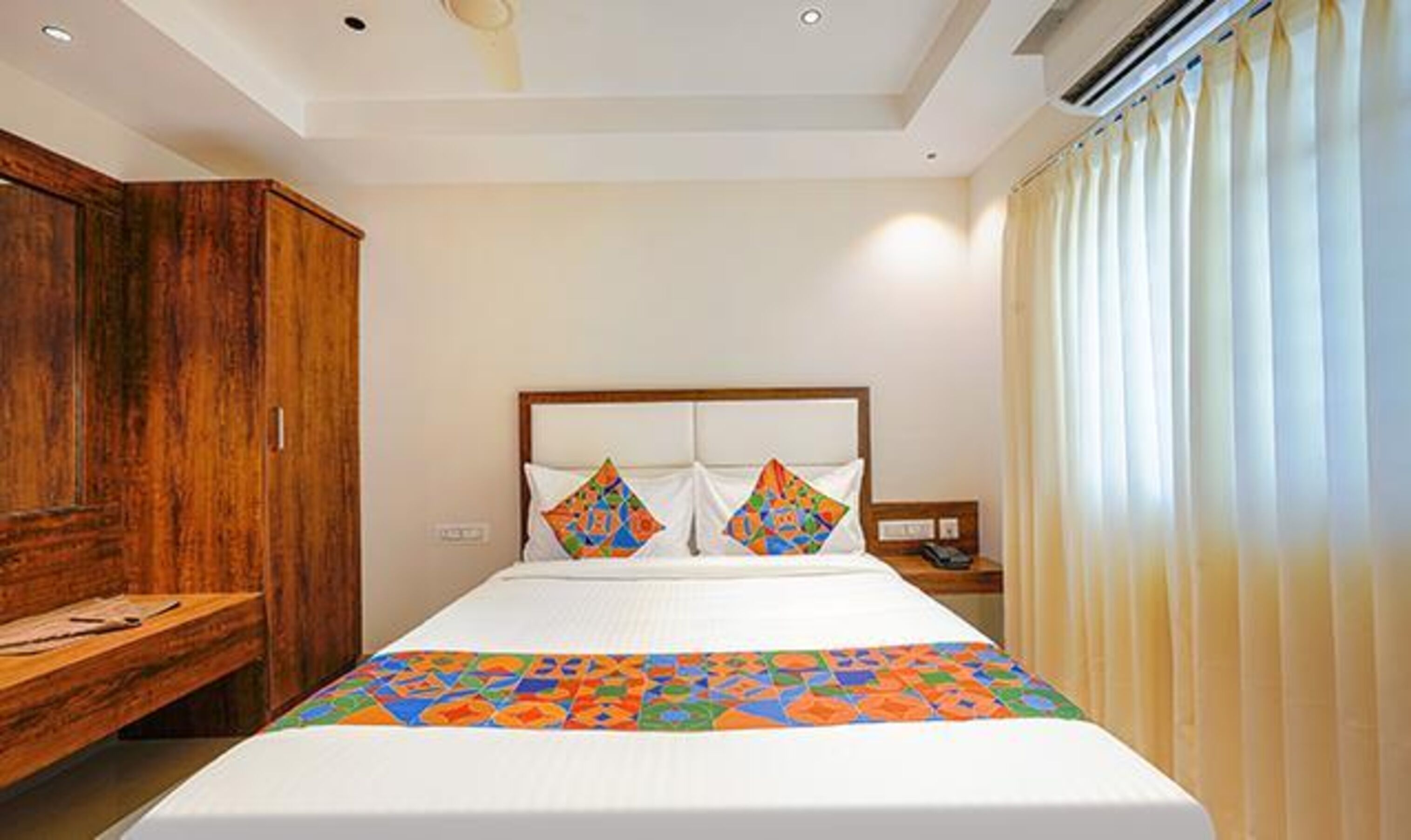Een hotelkamer met een groot bed, een houten garderobe en een nachtkastje.