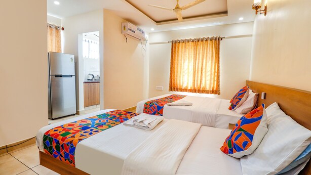 A hotel room with two beds, a refrigerator, a ceiling fan, and a window with curtains. - Fabhotel Green Park Residency (Bengaluru)