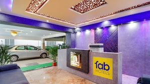 A hotel reception area with a reception desk, seating, and a car parked outside. - Fabhotel Green Park Residency (Bengaluru)