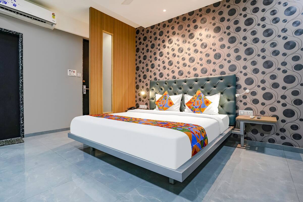 A modern bedroom with a large bed, a wooden door, and a patterned wall.