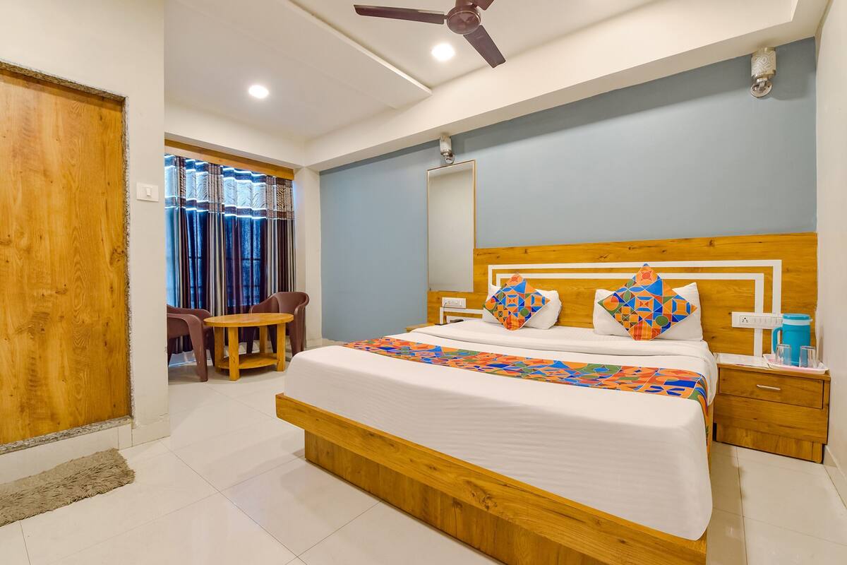A bedroom with a wooden bed, a nightstand, a ceiling fan, and a window with curtains.